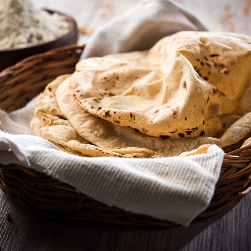 Indian Chapati or Fulka or Gehu Roti with wheat grains in background. It's a Healthy fibre rich traditional North or South Indian food, selective focus